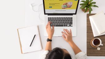 A person sitting at a desk with a laptop and a coffee cup