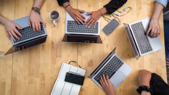 person using macbook pro on brown wooden table