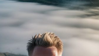A man takes a selfie on top of a mountain